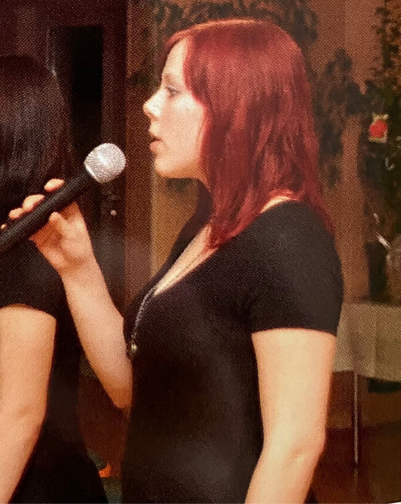 Johanna mit roten Haaren und Mikro in der Hand